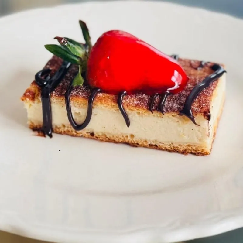 Cheesecake slice topped with a strawberry and chocolate drizzle